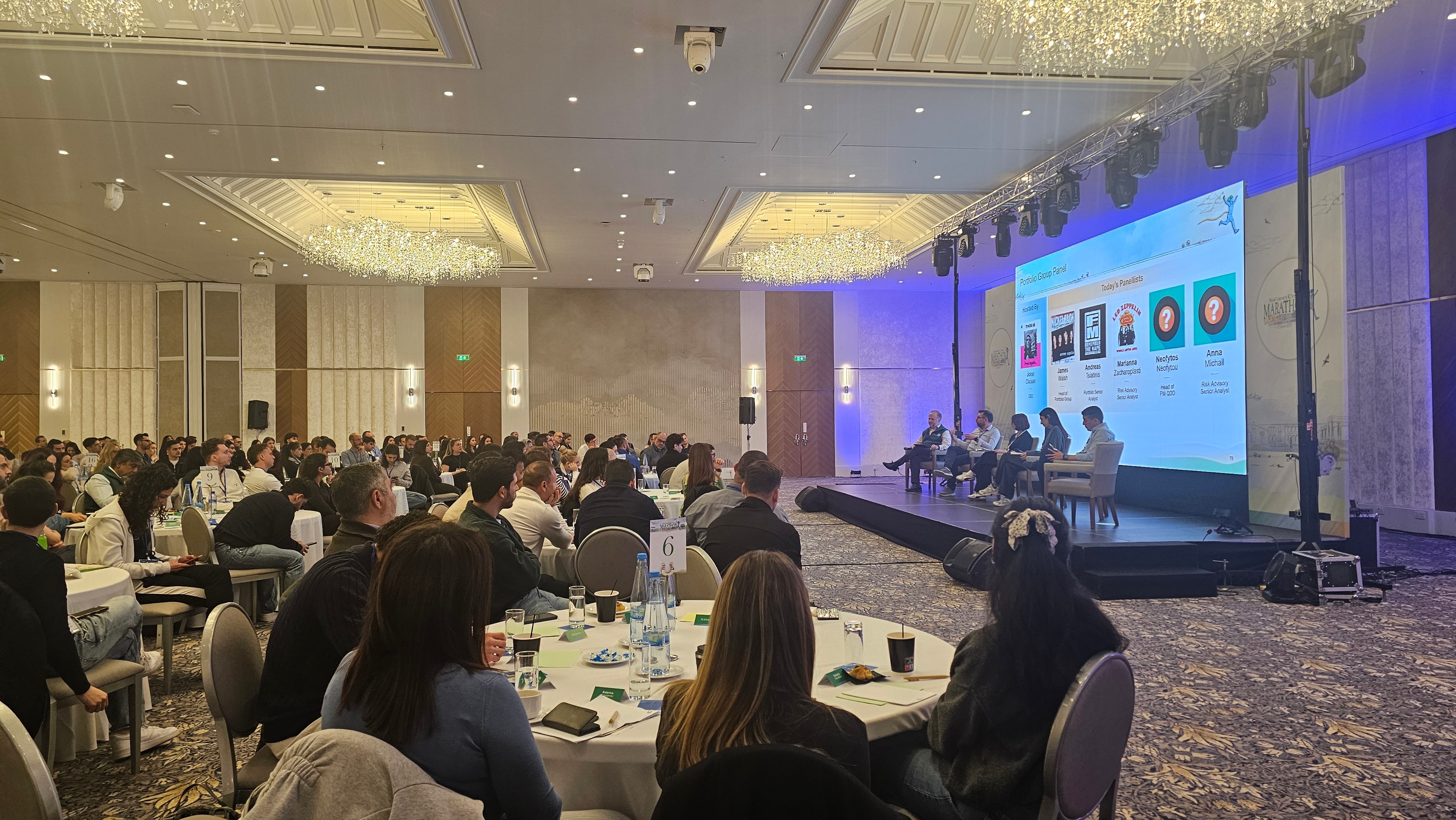 Large conference panel discussion with presentation screen and stage lighting